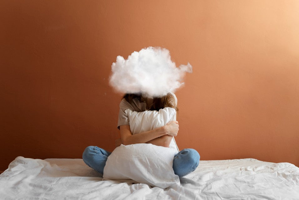 the green muse blog estress. mujer en la cama con una nube en lugar de su cerebro. fondo naranja. 
